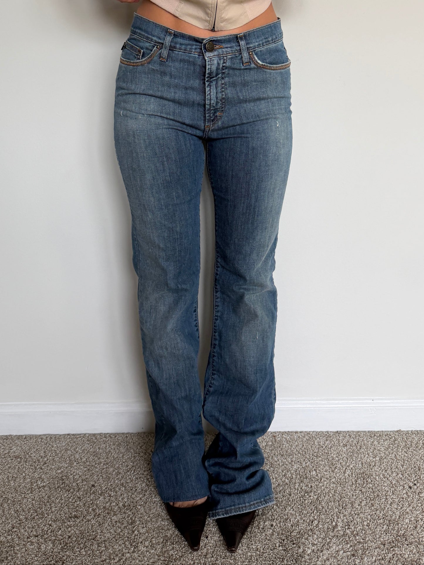 Person wearing blue jeans and a beige shirt against a plain background