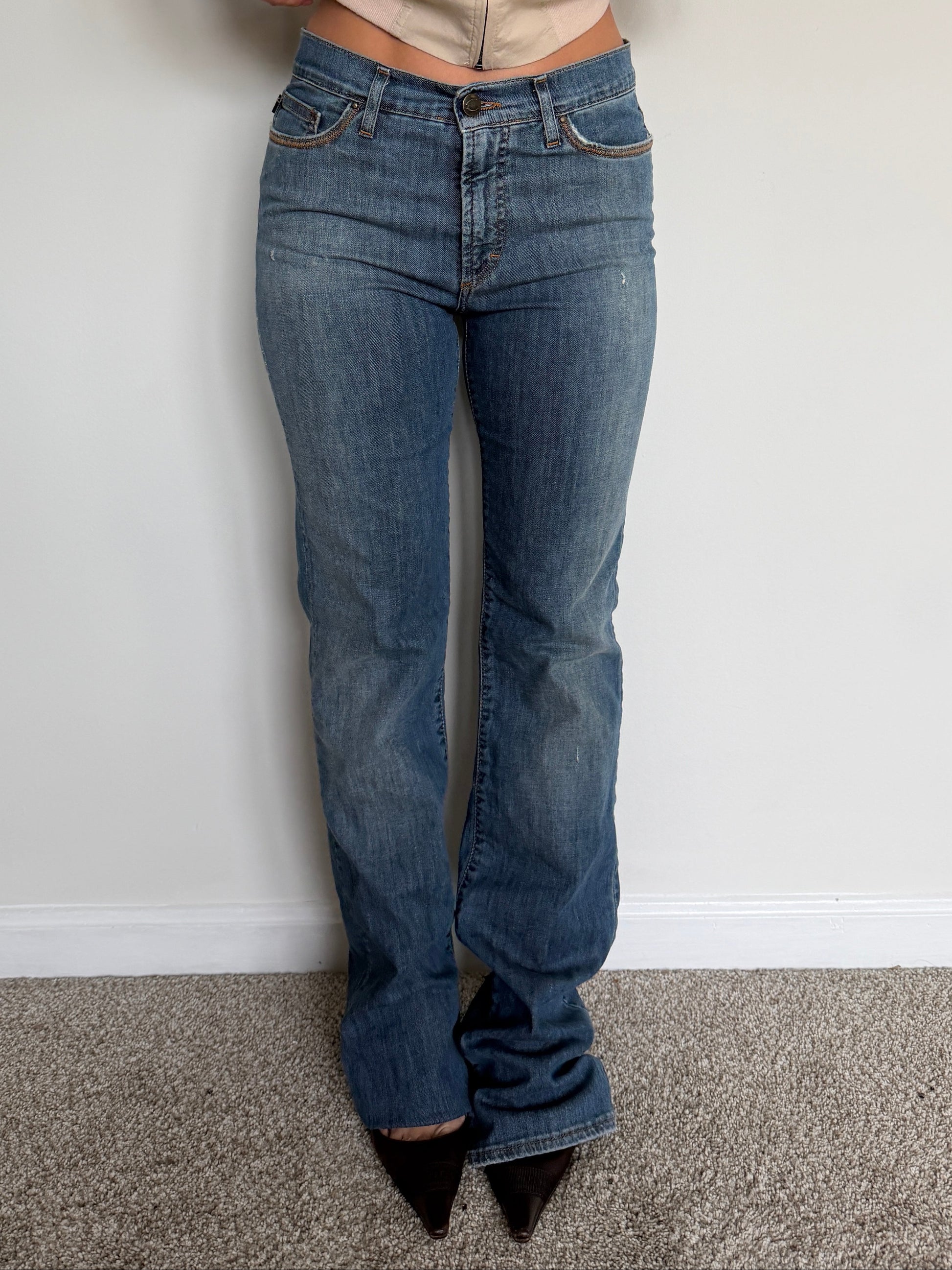 Person wearing blue jeans and a beige shirt against a plain background