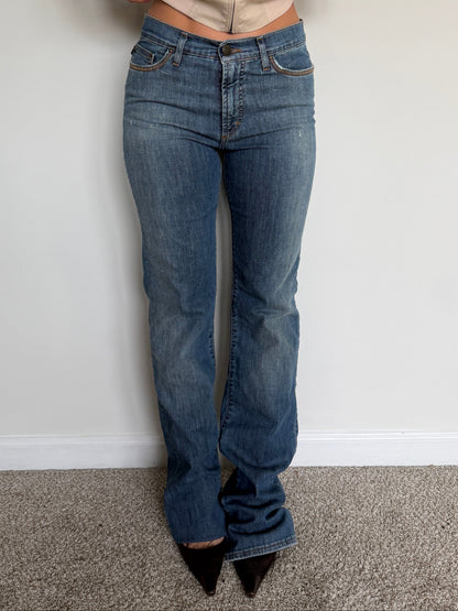 Person wearing blue jeans and a beige shirt against a plain background