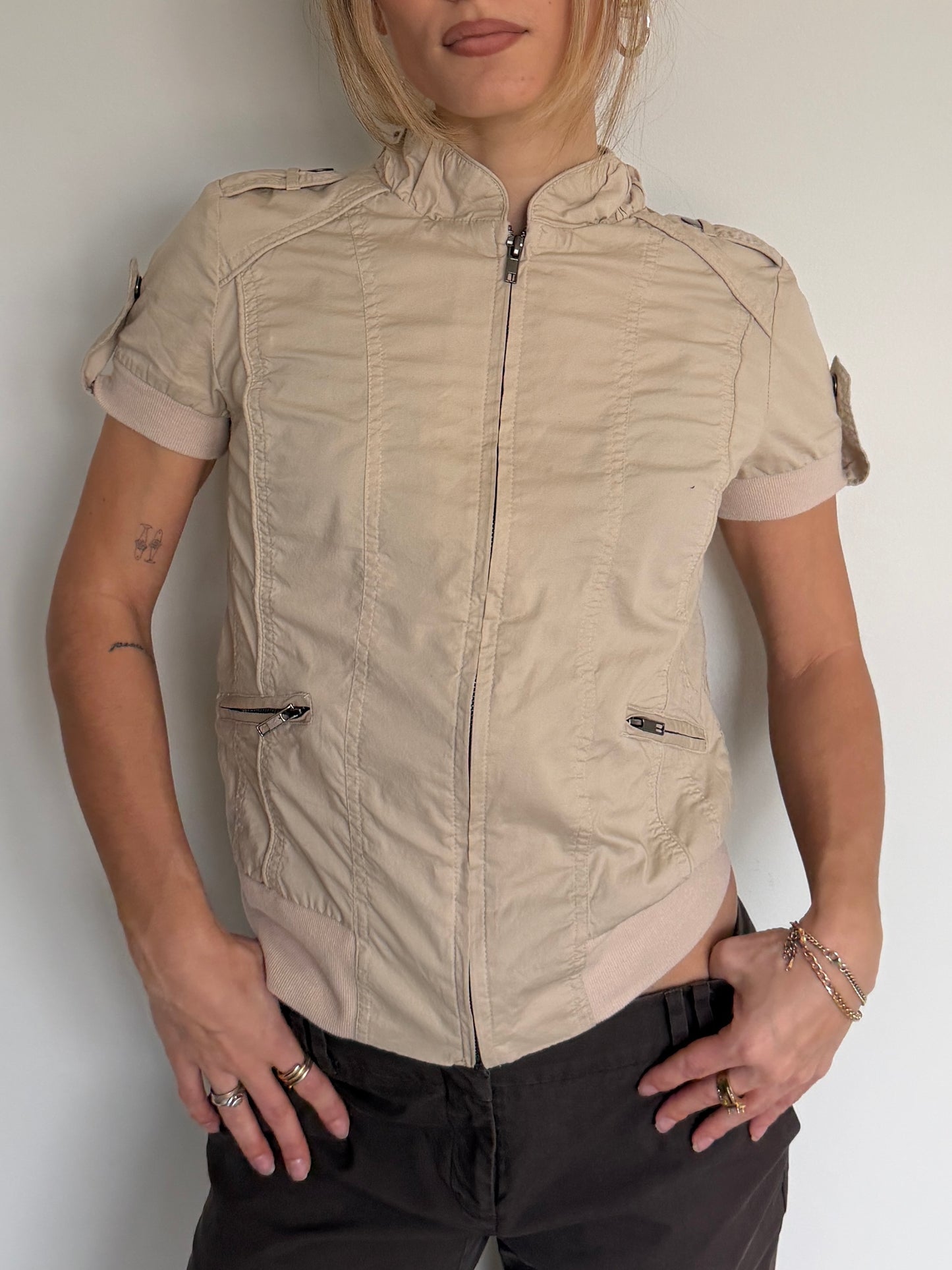Person wearing a beige short-sleeve jacket against a plain background