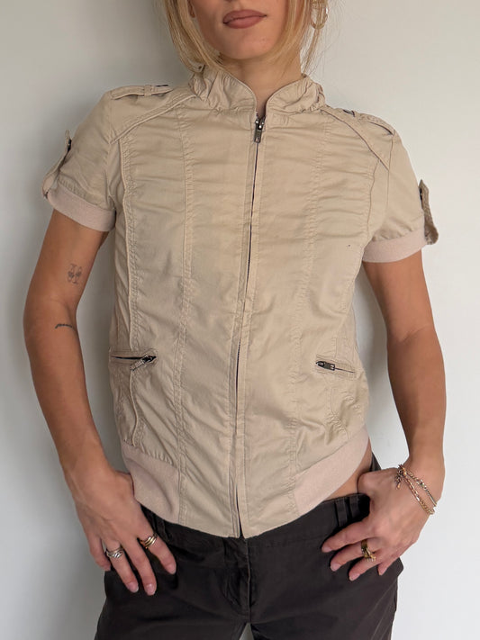 Person wearing a beige short-sleeve jacket against a plain background