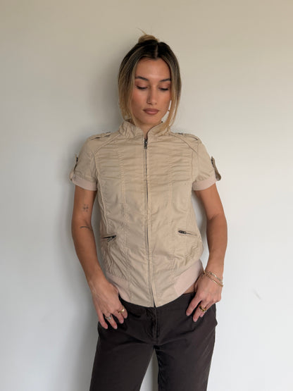 Woman wearing a beige short-sleeve jacket against a plain background