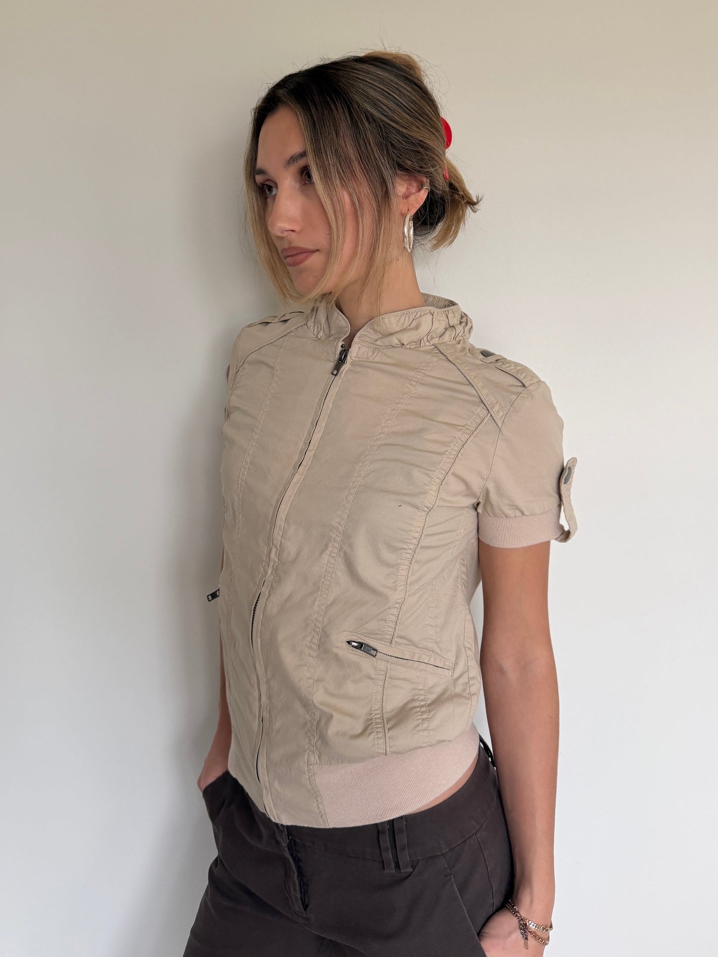 Woman wearing a beige short-sleeve jacket against a plain background
