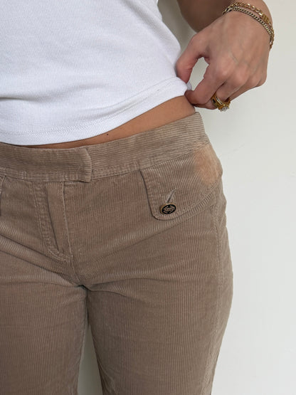 Brown corduroy pants worn by a person on a white background