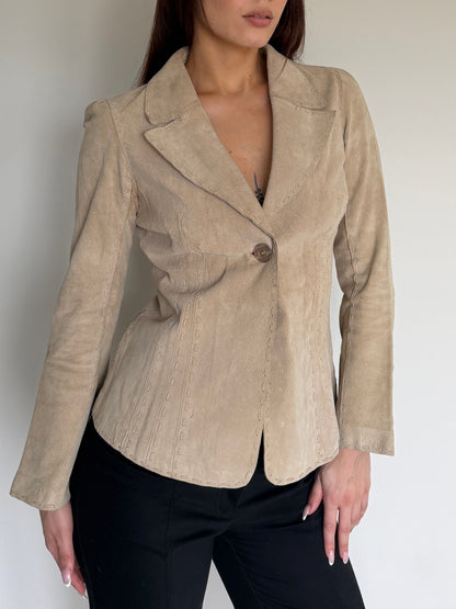 Woman wearing a beige blazer against a plain background
