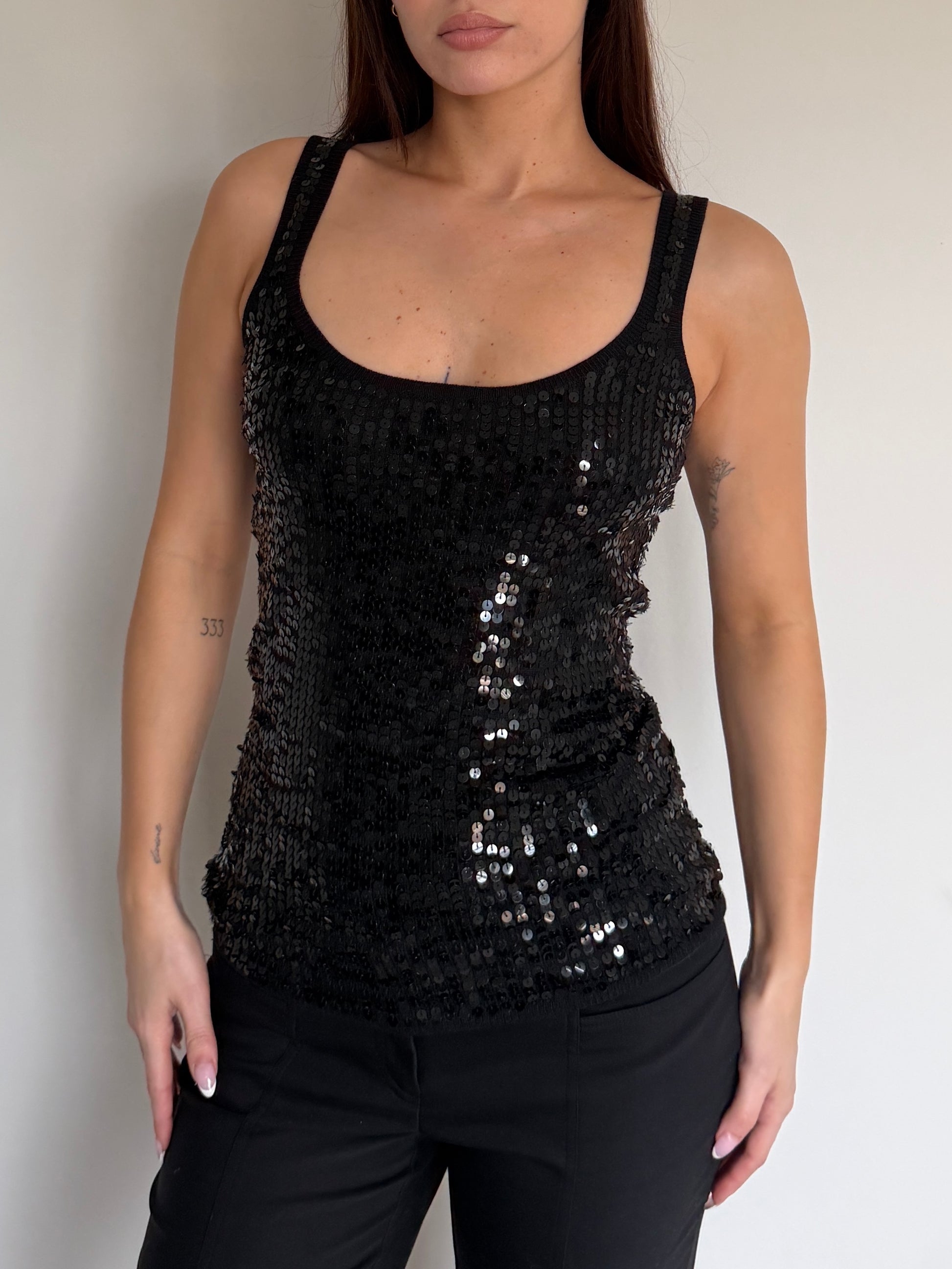Black sequin tank top worn by a person against a neutral background