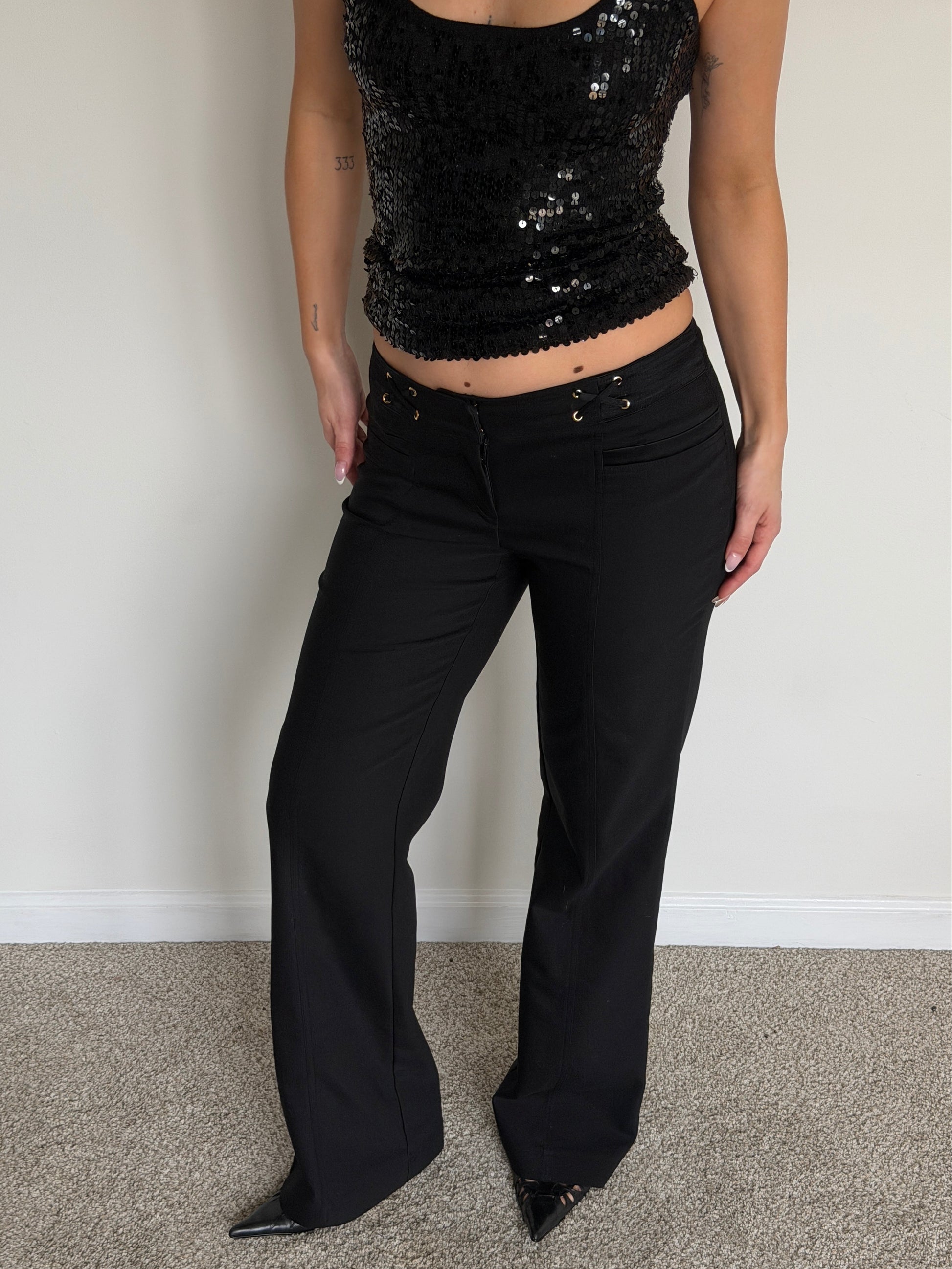 Person wearing a black sequin top and black pants against a plain background