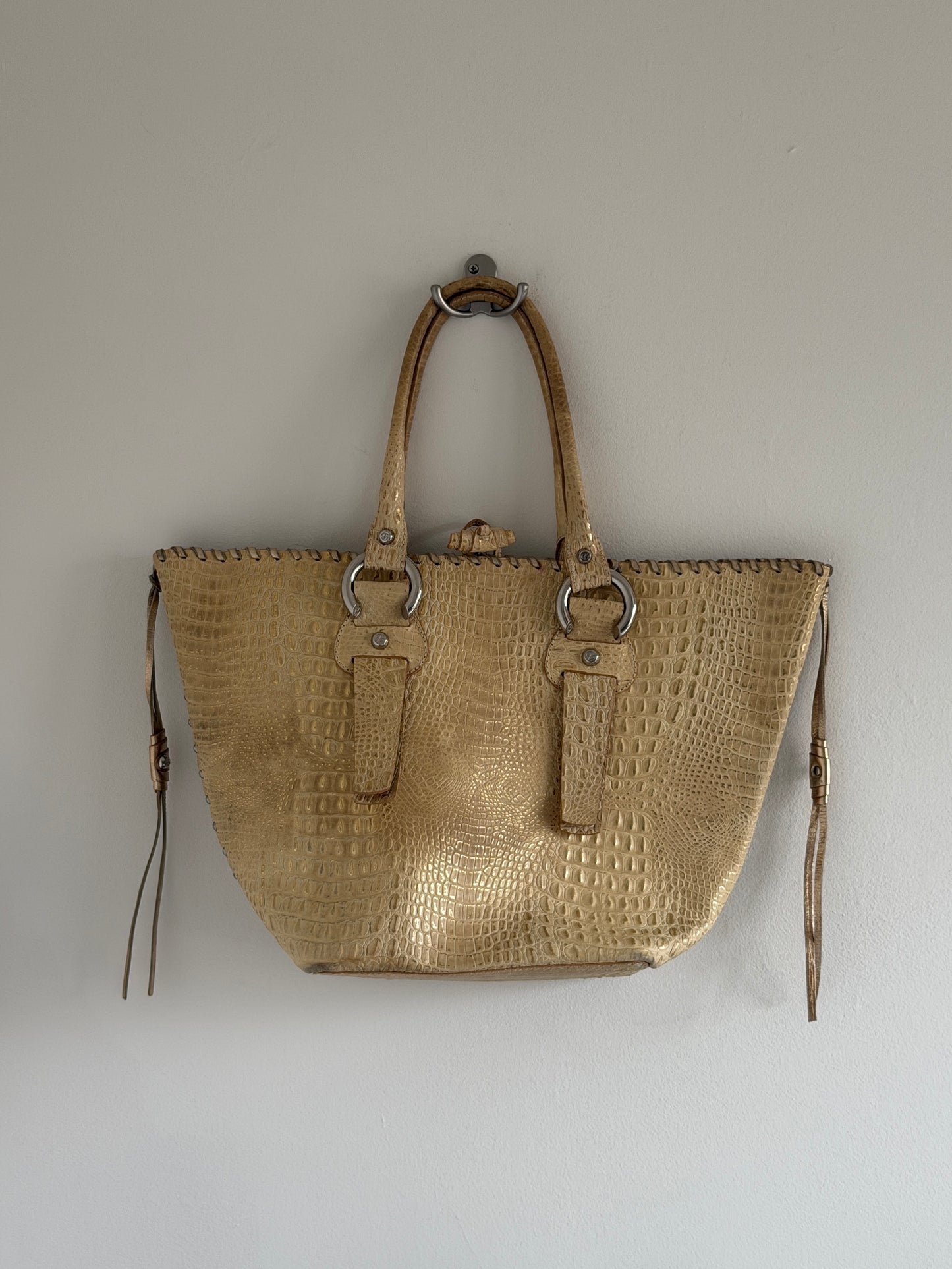 Beige textured handbag with metal rings on a light gray background
