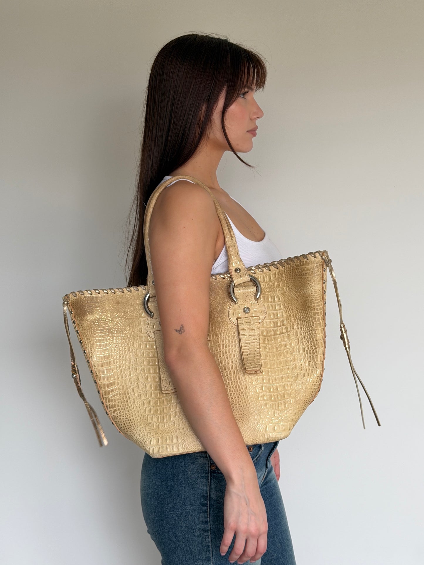 Woman holding a large straw bag against a plain background