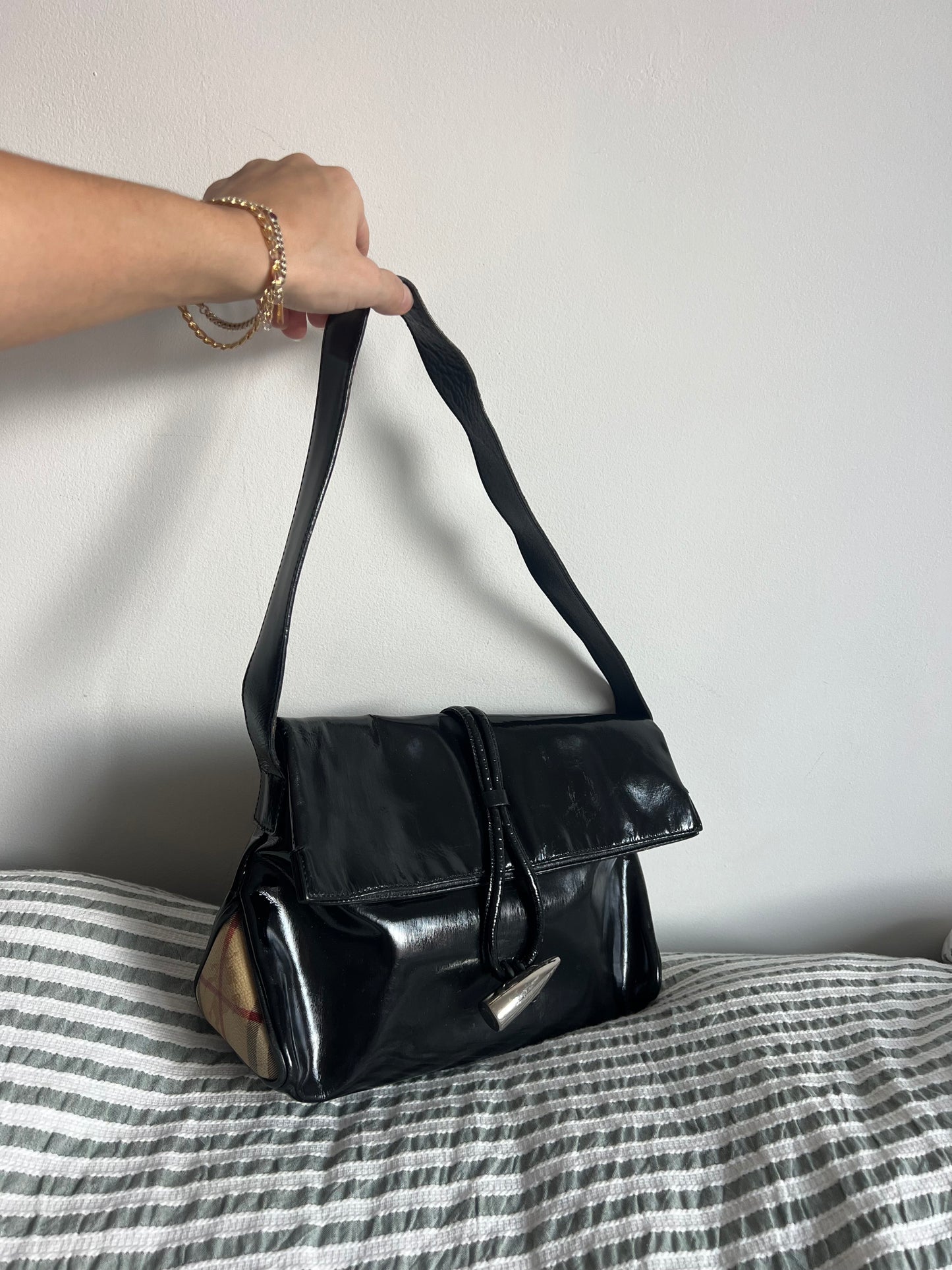 Black handbag held by a person on a striped fabric background