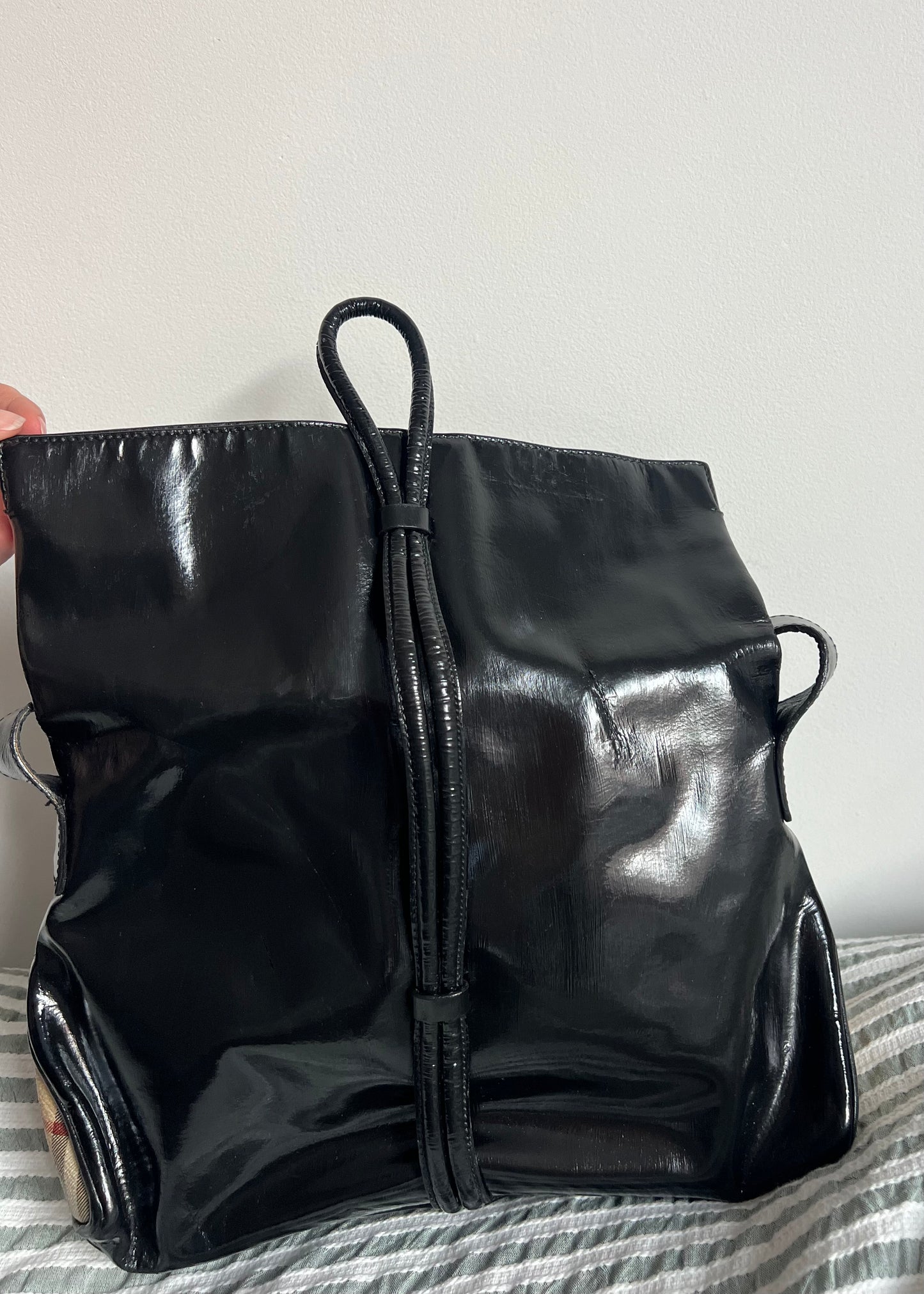 Black shiny backpack on a striped fabric background