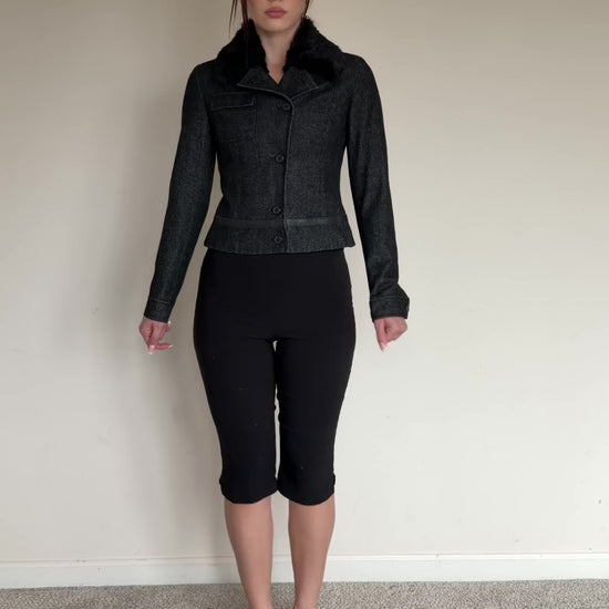 Dark gray jacket with fur collar worn by a person on a plain background