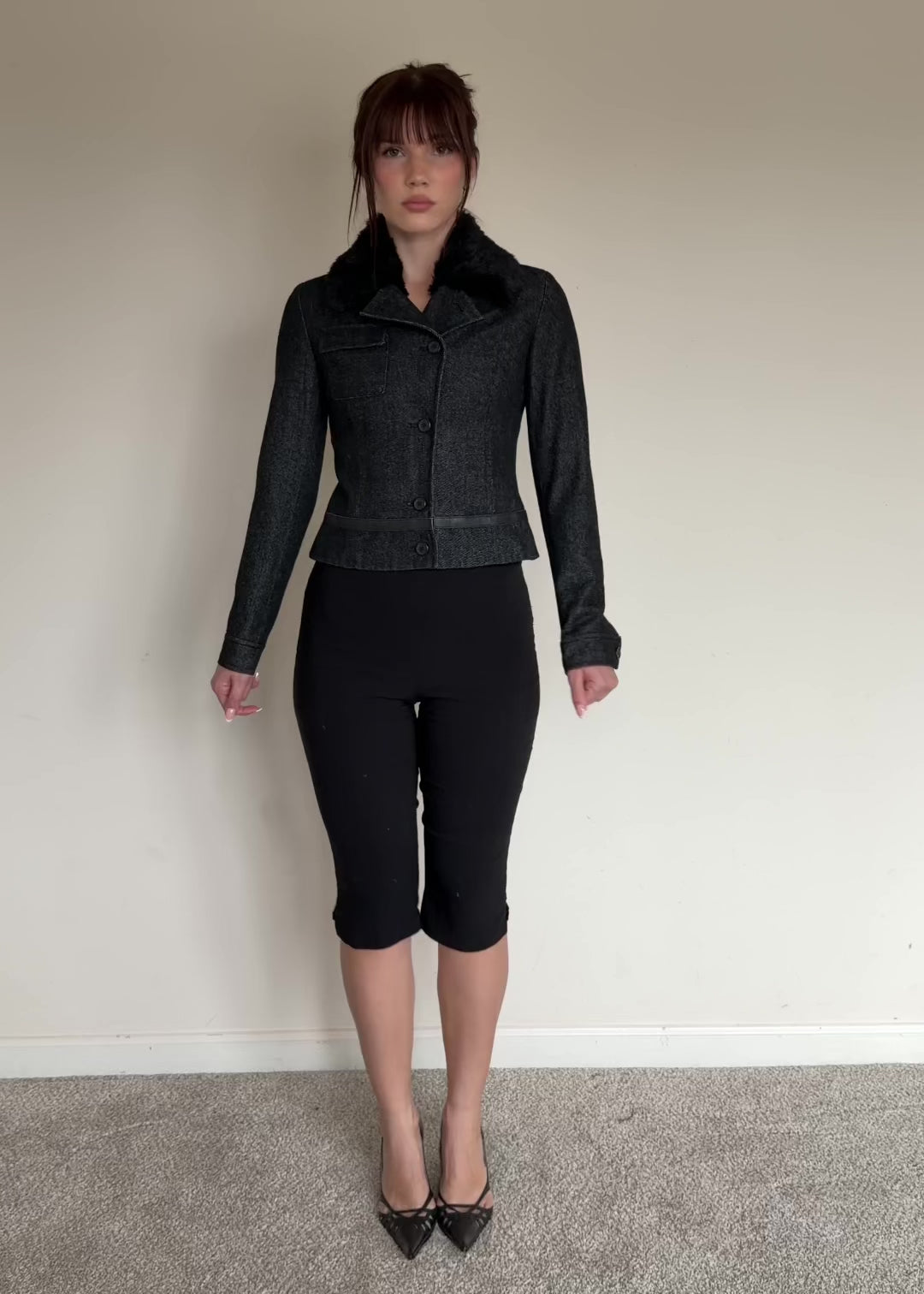 Dark gray jacket with fur collar worn by a person on a plain background