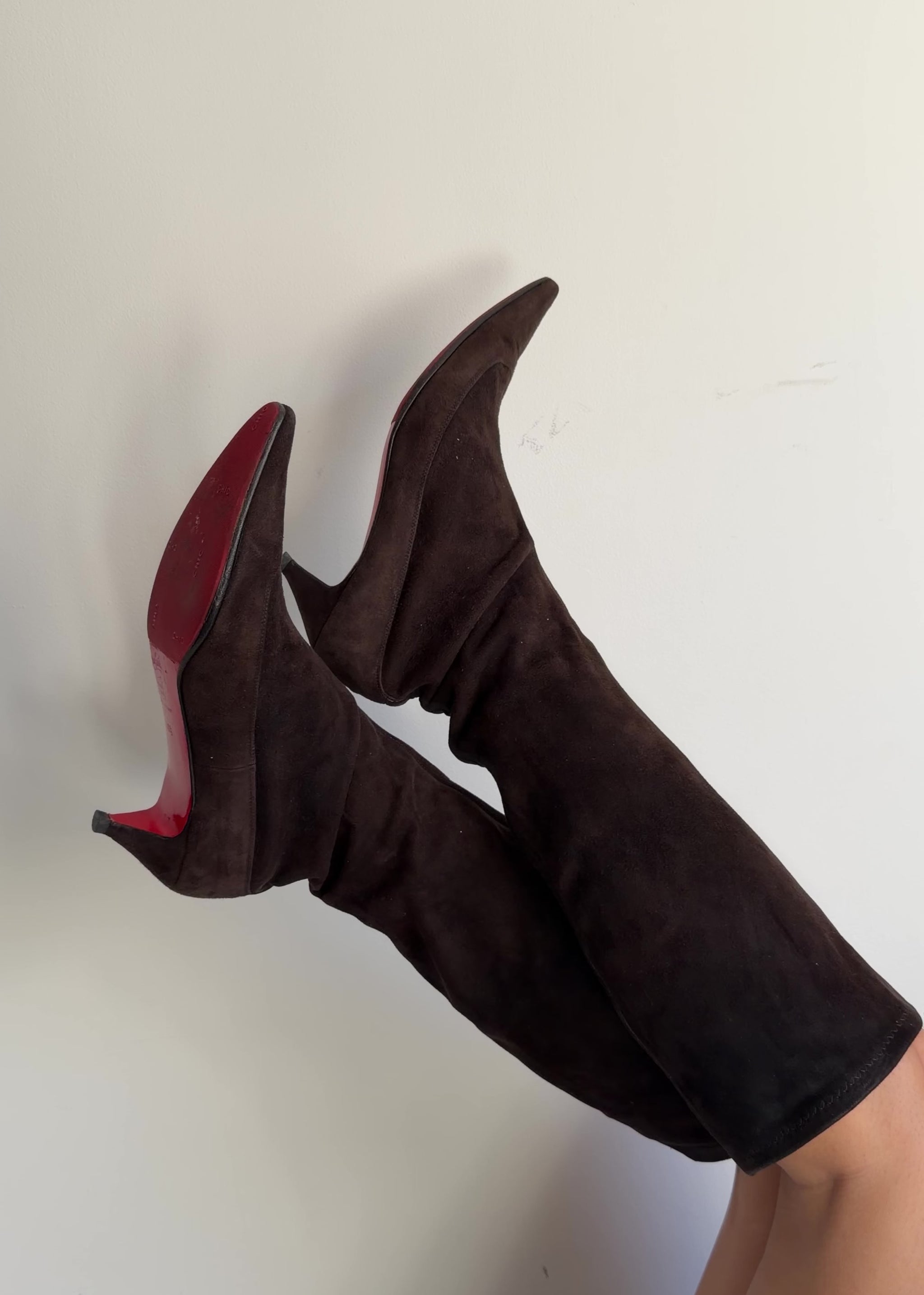 Brown knee-high boots worn by a person on a plain background